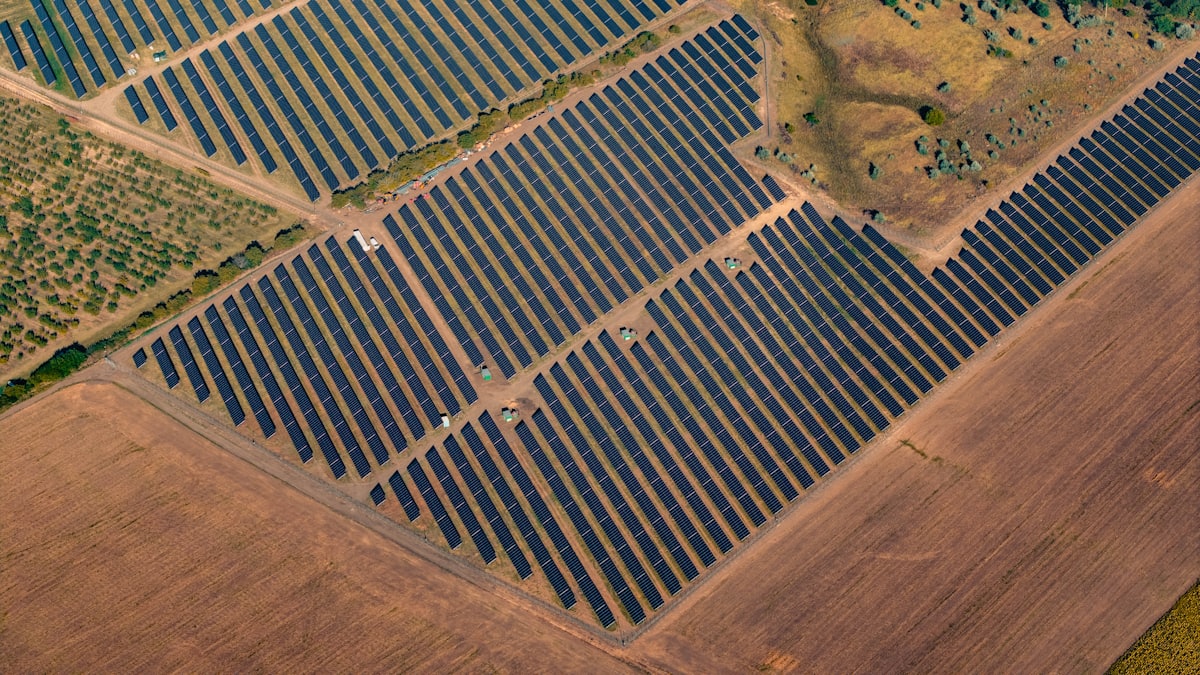 Aerial view of a ground-mounted solar farm with rows of panels